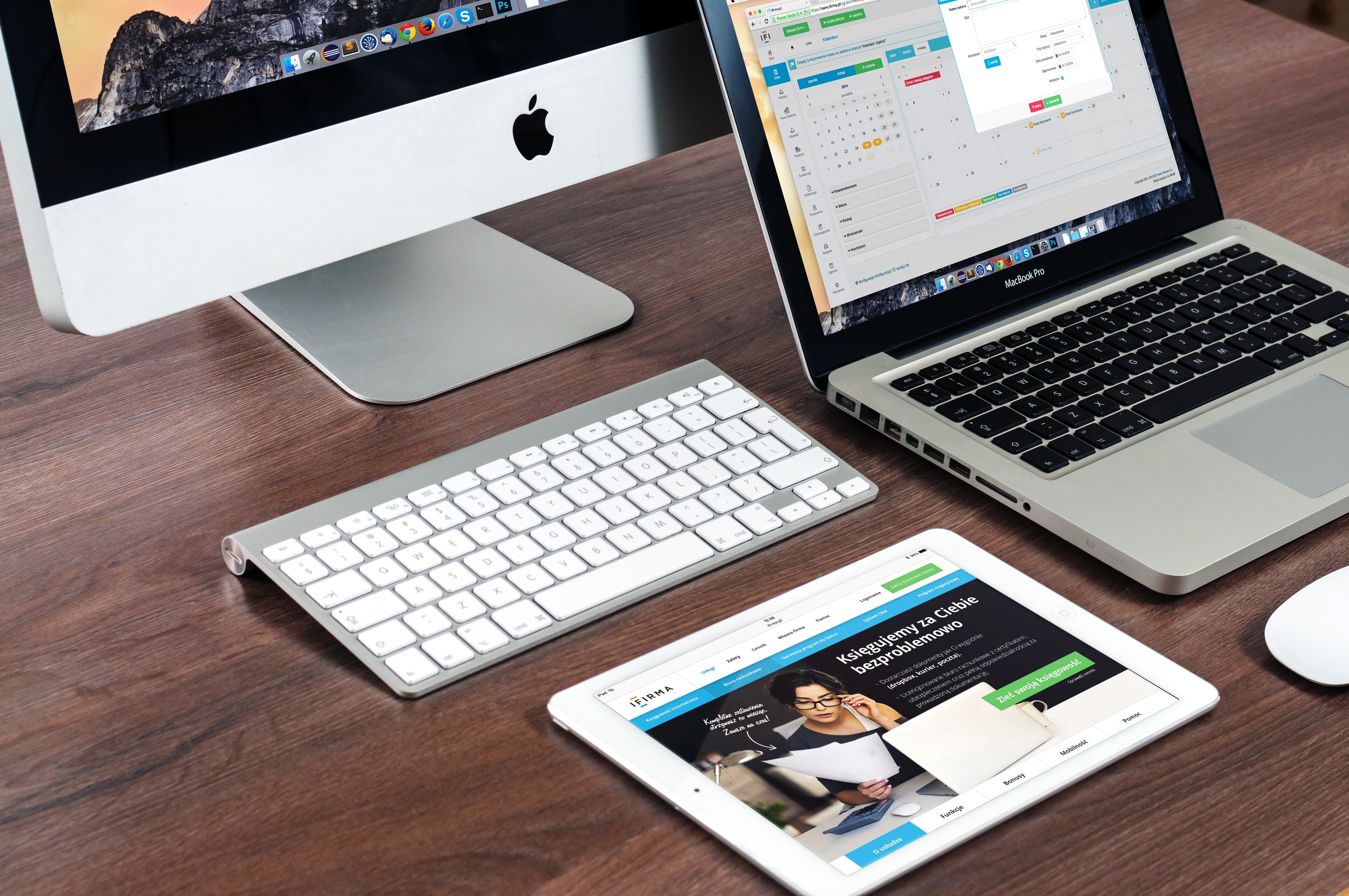 a computer, laptop, and tablet on a desk